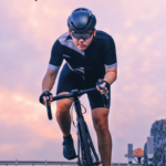 Young man riding a roadbike with a hazy pink background.